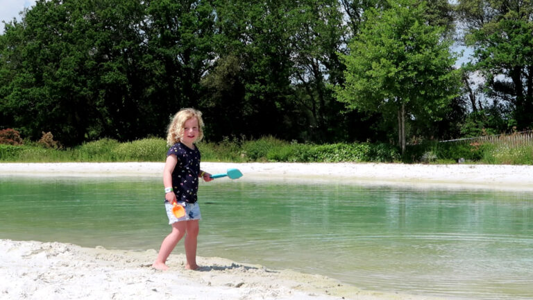 A child playing on the sandy beach beside the lagoon pool at La Garangeoire