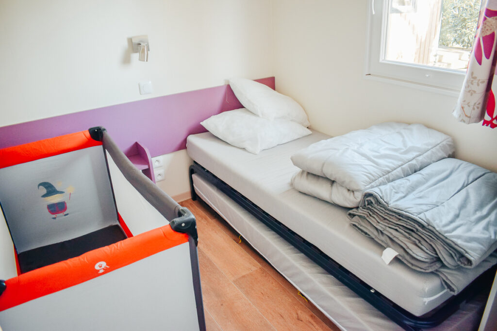 Cot in the twin bedroom of the Cottage loupiac at yelloh village camping lac du bordeaux