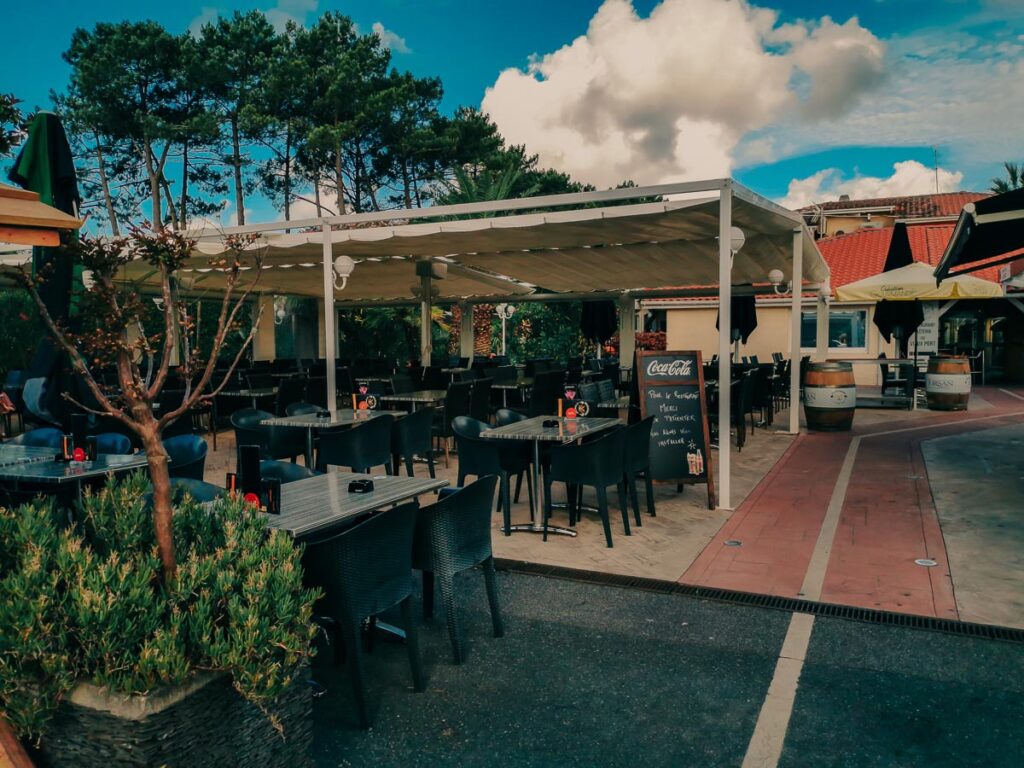 seating area with tables and chairs with covered canopy in the restaurant at camping le vieux port by Resasol in Messanges, Landes department, France