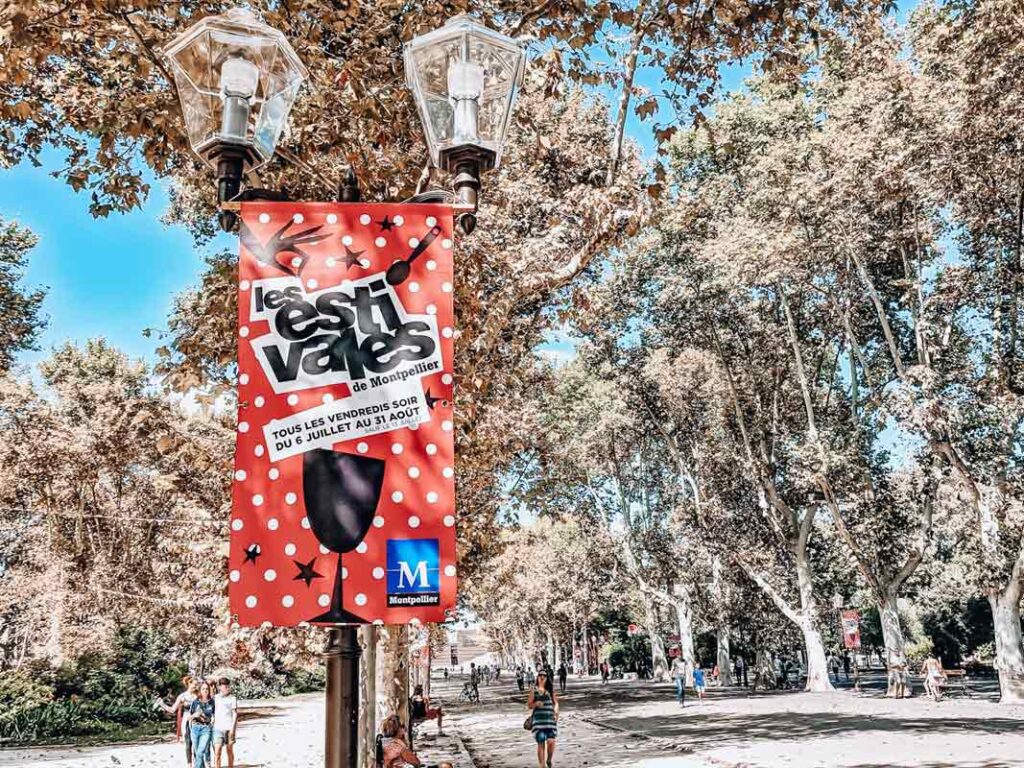 A sign about the estivales in charles de gaulle esplanade a location in montpellier. photo of signs, lamps and trees