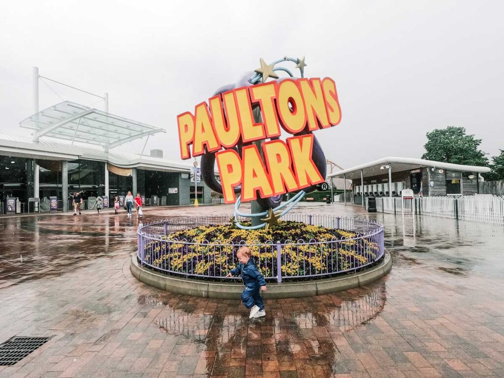 the toddler in front of the paultons park sign in the rain