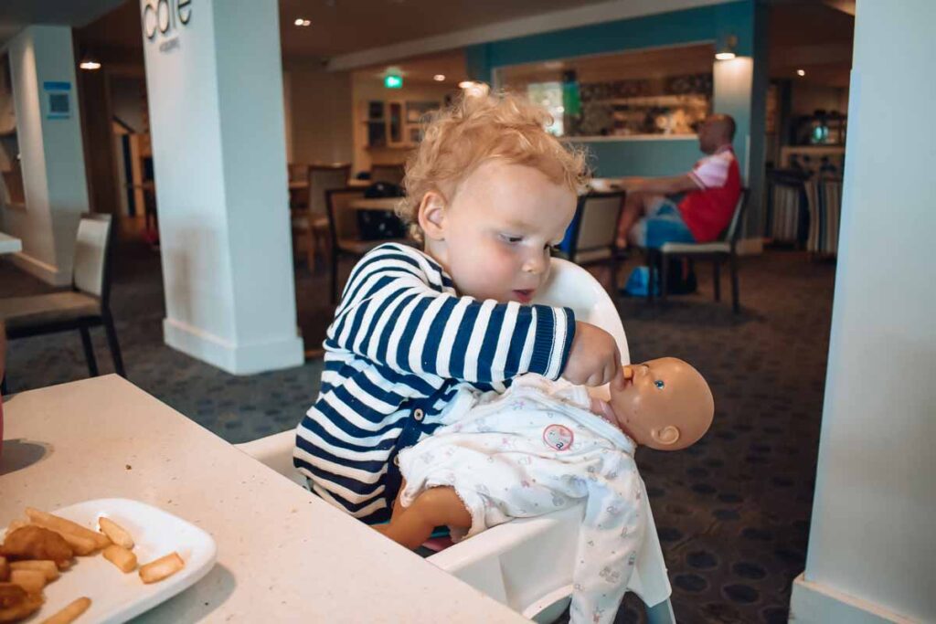 toddler-feeding-her-baby-doll-at-the-bar-area-in-hoburne-bashley-park-campsite