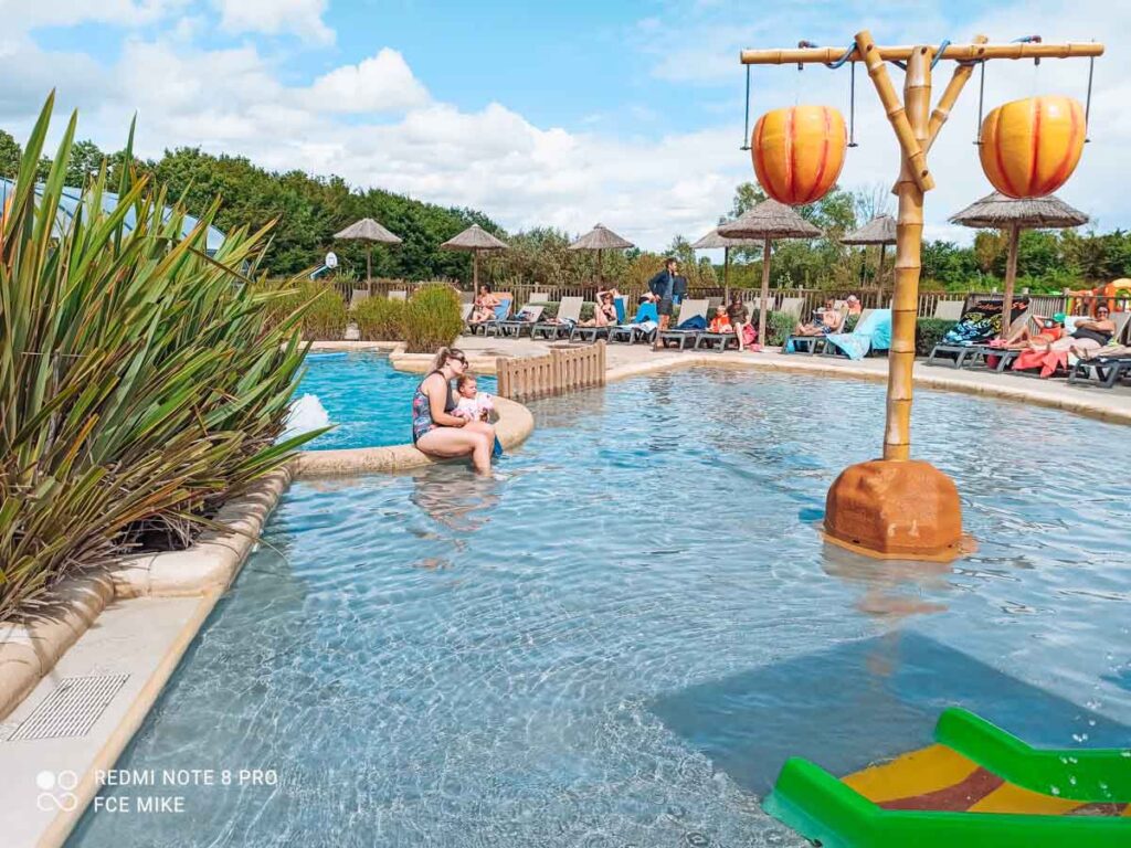 Breanne and the toddler sat at the pool at camping la roche posay yelloh village