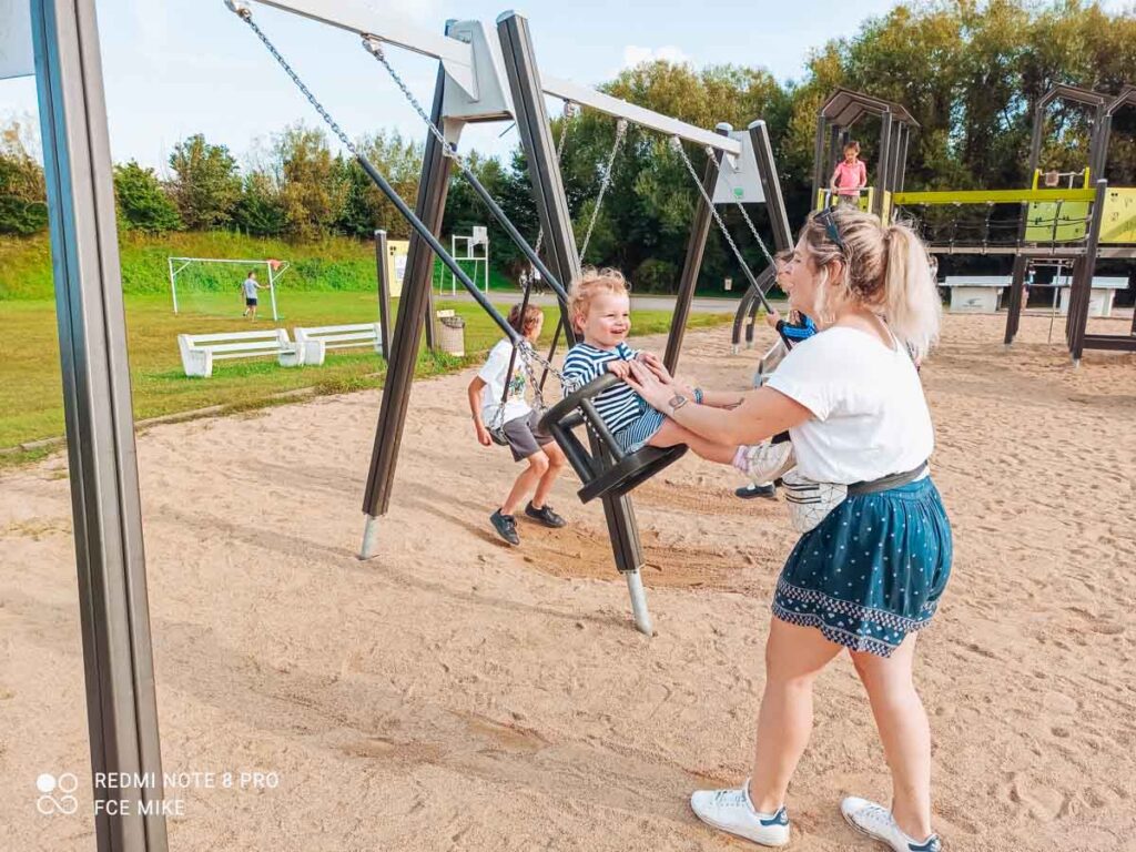 TODDLER PLAYING ON A BABY SWING AT ONE OF THE BMOST TODDLER FRIENDLY CAMPSITES IN fRANCE CAMPING LA ROCHE POSAY