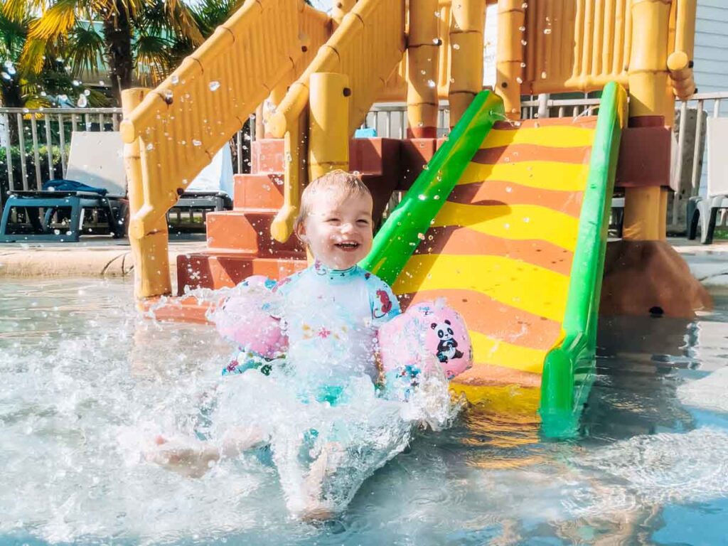 toddler on the kids water slide at camping la roche posay yelloh village campsite