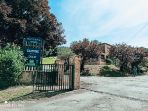 This is the entrance to teh Huttopia Sarlat campsite with green sign and trees