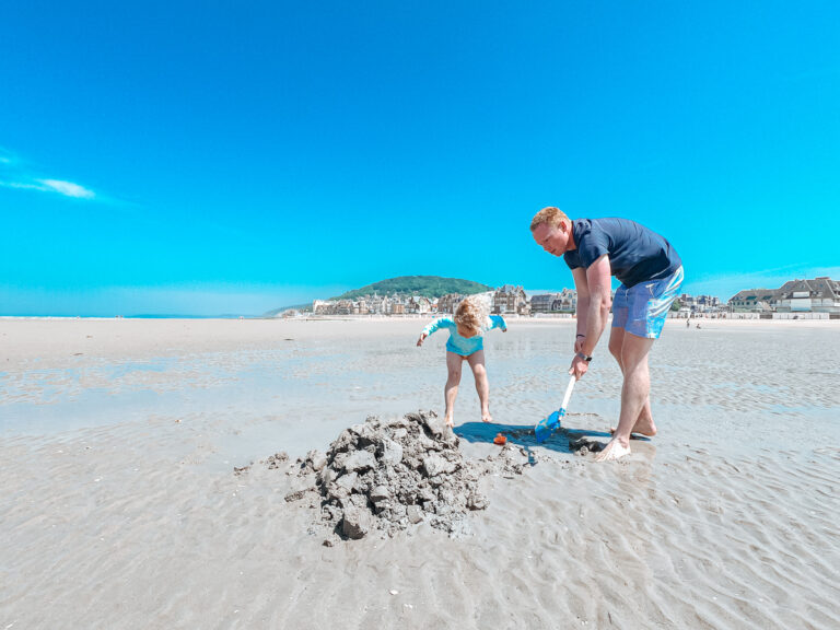 A man and children digging in the sand on Houlgate Beach