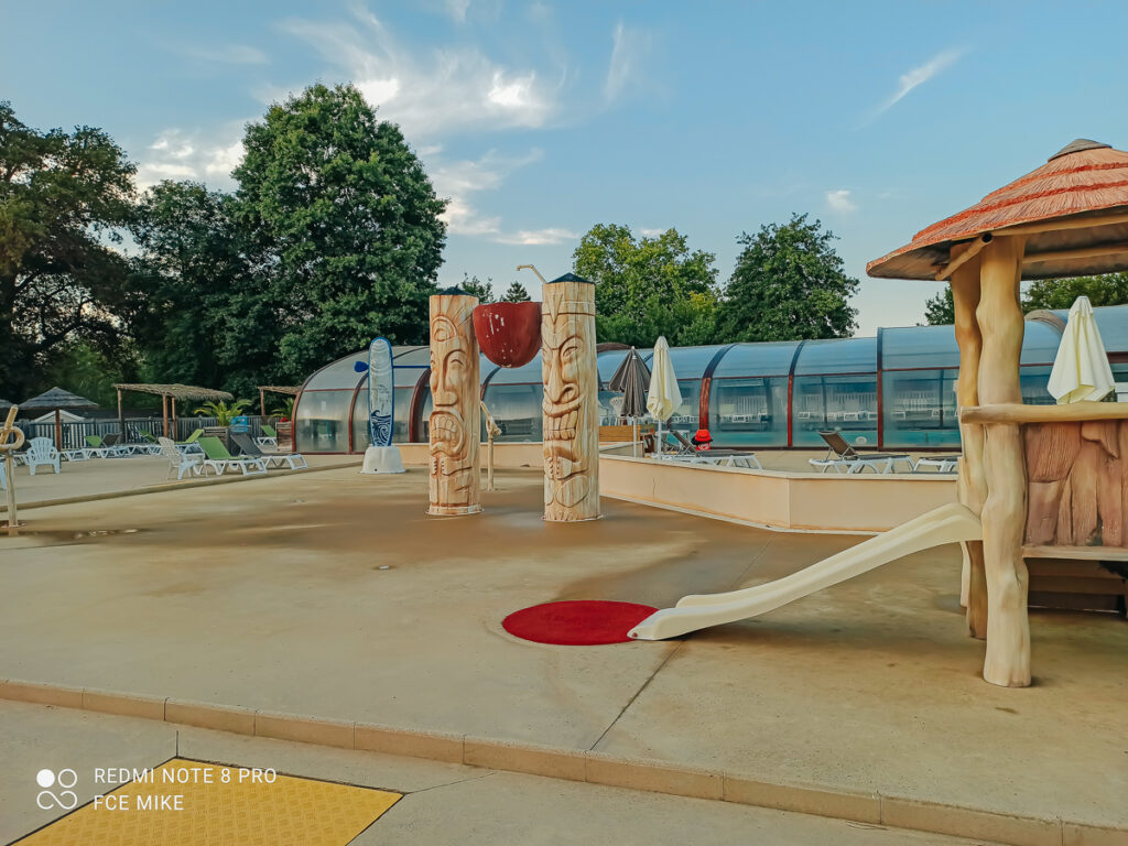 a small splash park near the swimming pool with kids slide and water sprays