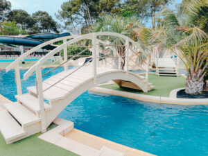 a picture of a blue swimming pool with a white bridge over the top at l'oree du bois