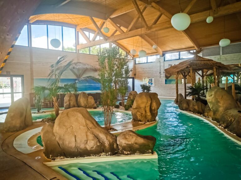 Indoor pool with rock features and a lazy river at Yelloh Village La Rive