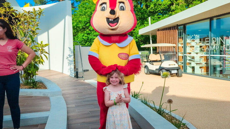 A woman and a child with a squirrel mascot at Yelloh! Village campsite