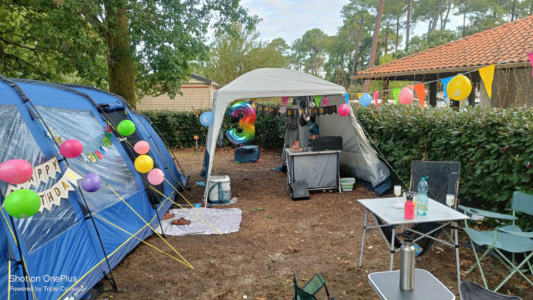 Tent pitch with picnic table and bunting at Camping du Réjallant