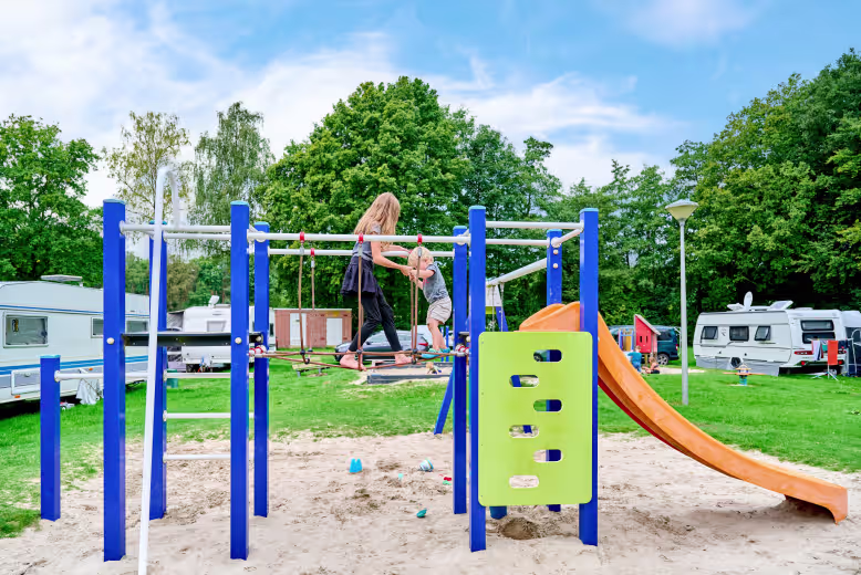 eurocamp netherlands site klein vink with children playing in the park  with campervans behind them