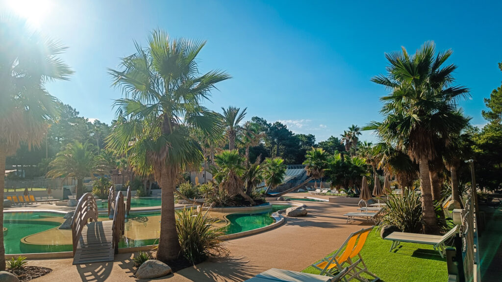 another view of the pool area with waterslides, deck chairs and palm trees at camping cote d'argent