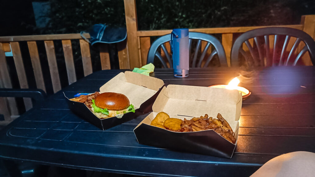 A takeaway burger and chips on the decking in the evening